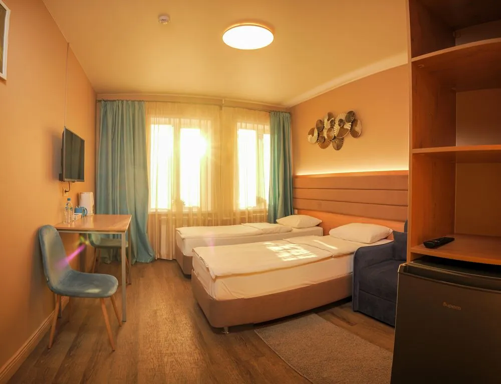 Трёхместный номер светлый с отдельными кроватями и креслом